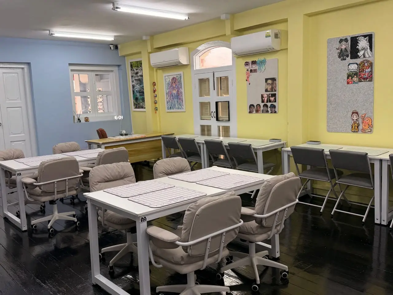 Long shared tables set with pegboards for a group, in the studio's blue and yellow room